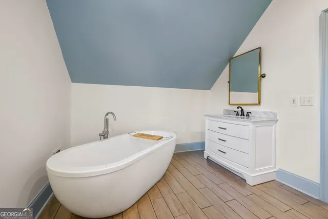a bathroom with a white tub sink and mirror