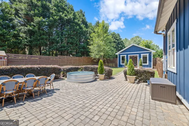 a view of a patio with table and chairs near a barbeque