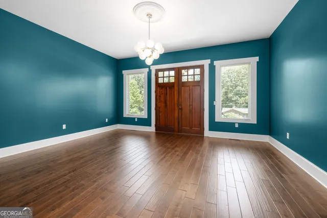 an empty room with wooden floor and windows