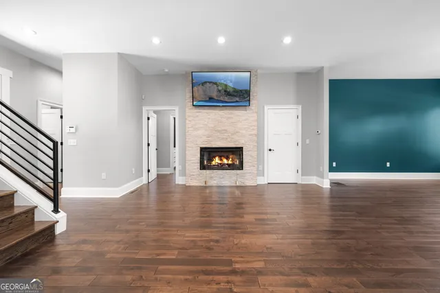a view of an empty room with wooden floor and a fireplace