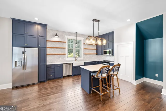 a kitchen with stainless steel appliances a dining table chairs stove refrigerator and cabinets