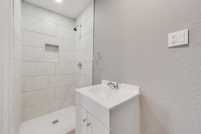 930 Freeman Street Sherman, TX 75092 - Photo 12 of 18 Contemporary bathroom featuring a compact vanity with integrated sink, chrome faucet, and white cabinetry