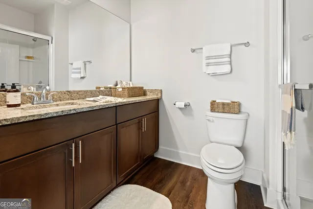 a bathroom with a granite countertop toilet sink and mirror