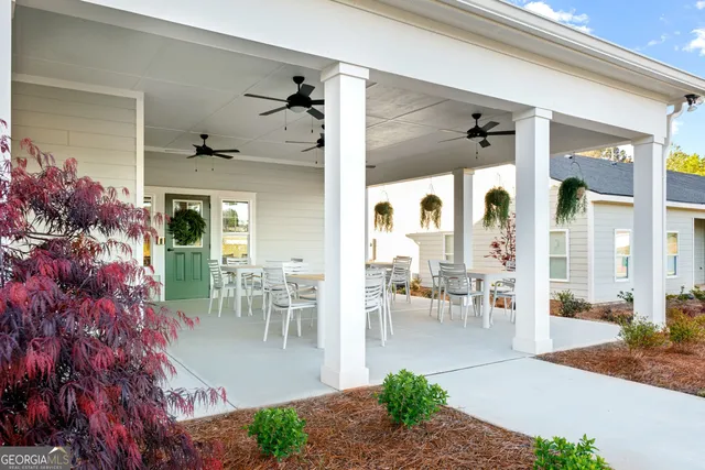 a view of a patio with table and chairs potted plants and floor to ceiling window