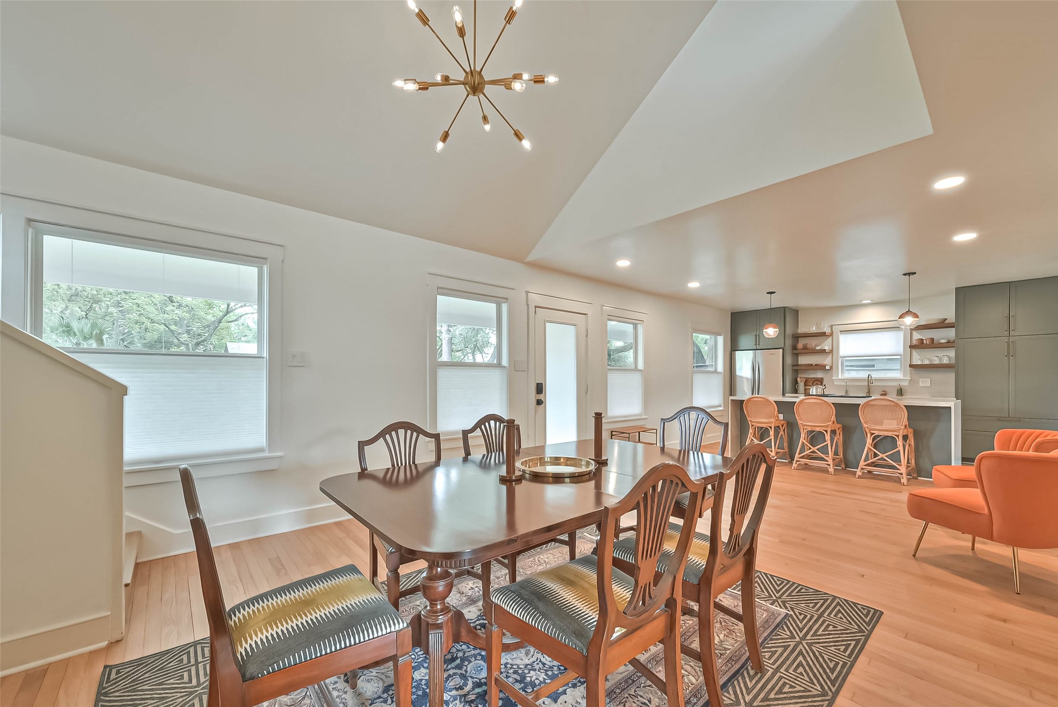 412 Sue Street Houston, TX 77009 - Photo 5 of 19 This open-concept living/dining space features a modern dining area with a stylish light fixture, open ceiling, and a contemporary kitchen with bar seating. Natural light fills the room through multiple windows, highlighting the warm wood flooring and sleek design.