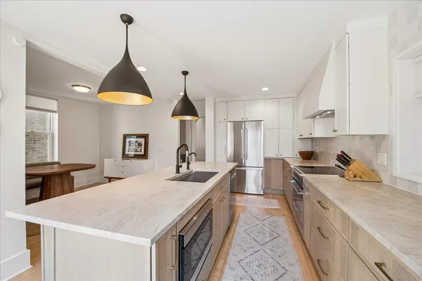 a kitchen with a stove a sink a refrigerator and a wooden floor