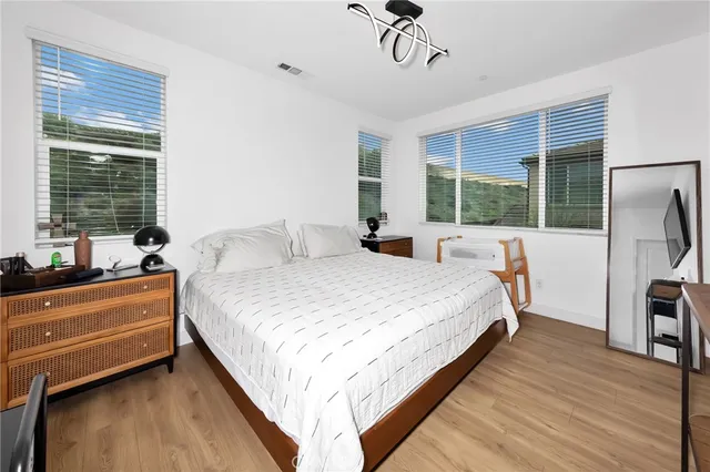 a spacious bedroom with a bed a flat screen tv and a large window with the outer view
