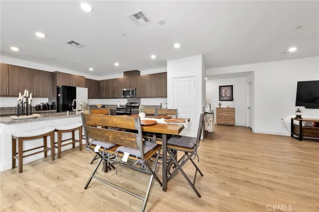 a living room with stainless steel appliances kitchen island granite countertop a table chairs and a refrigerator