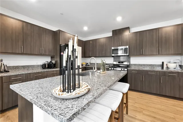 a kitchen with stainless steel appliances granite countertop a sink refrigerator and cabinets