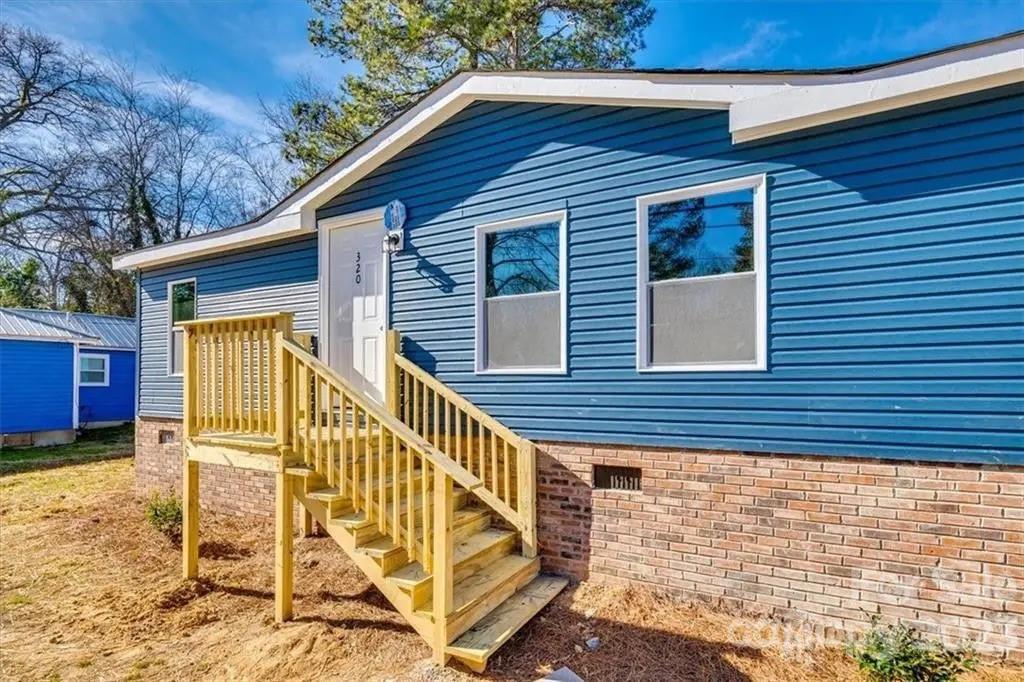 a view of wooden house with a small yard