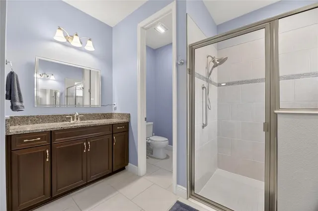 a bathroom with a granite countertop shower sink vanity and mirror