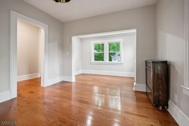 an empty room with wooden floor and a window