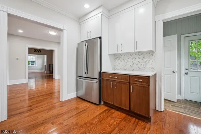 a kitchen with granite countertop wooden floors a refrigerator and cabinets