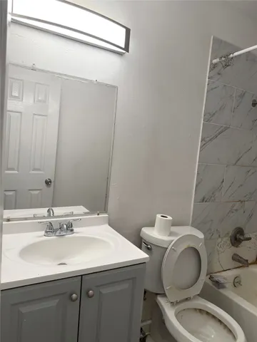 a bathroom with a granite countertop toilet sink and mirror
