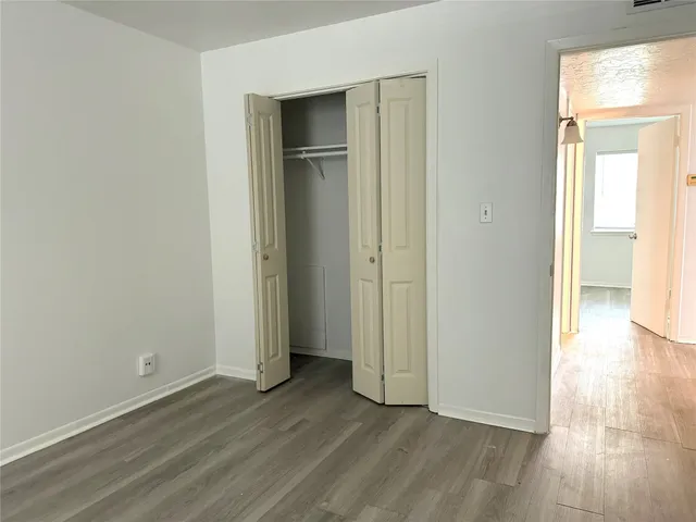 an empty room with wooden floor & windows