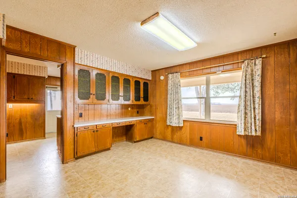 a large white kitchen with stainless steel appliances granite countertop a stove and a large window