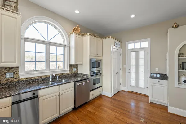 a kitchen with granite countertop a sink a stove and cabinets