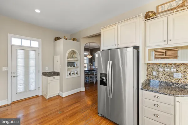 a kitchen with stainless steel appliances granite countertop a refrigerator a sink dishwasher a stove and white countertops with wooden floor