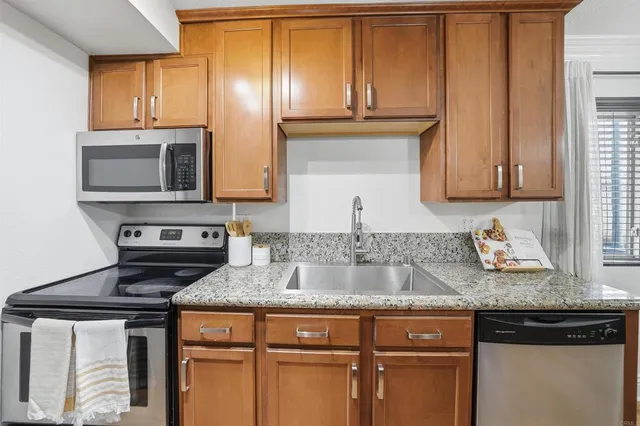 a kitchen with granite countertop cabinets stainless steel appliances and a sink