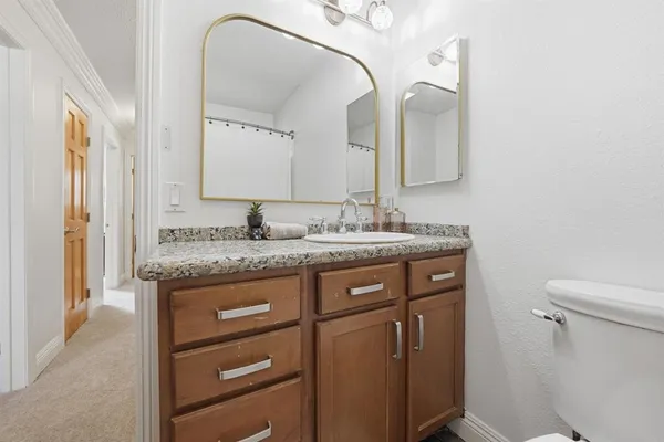 a bathroom with a granite countertop sink a toilet and a mirror