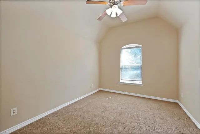 an empty room with a chandelier fan and window