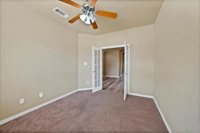 an empty room with closet and a chandelier fan