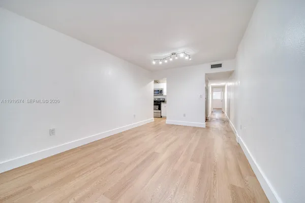 an empty room with wooden floor chandelier fan and windows