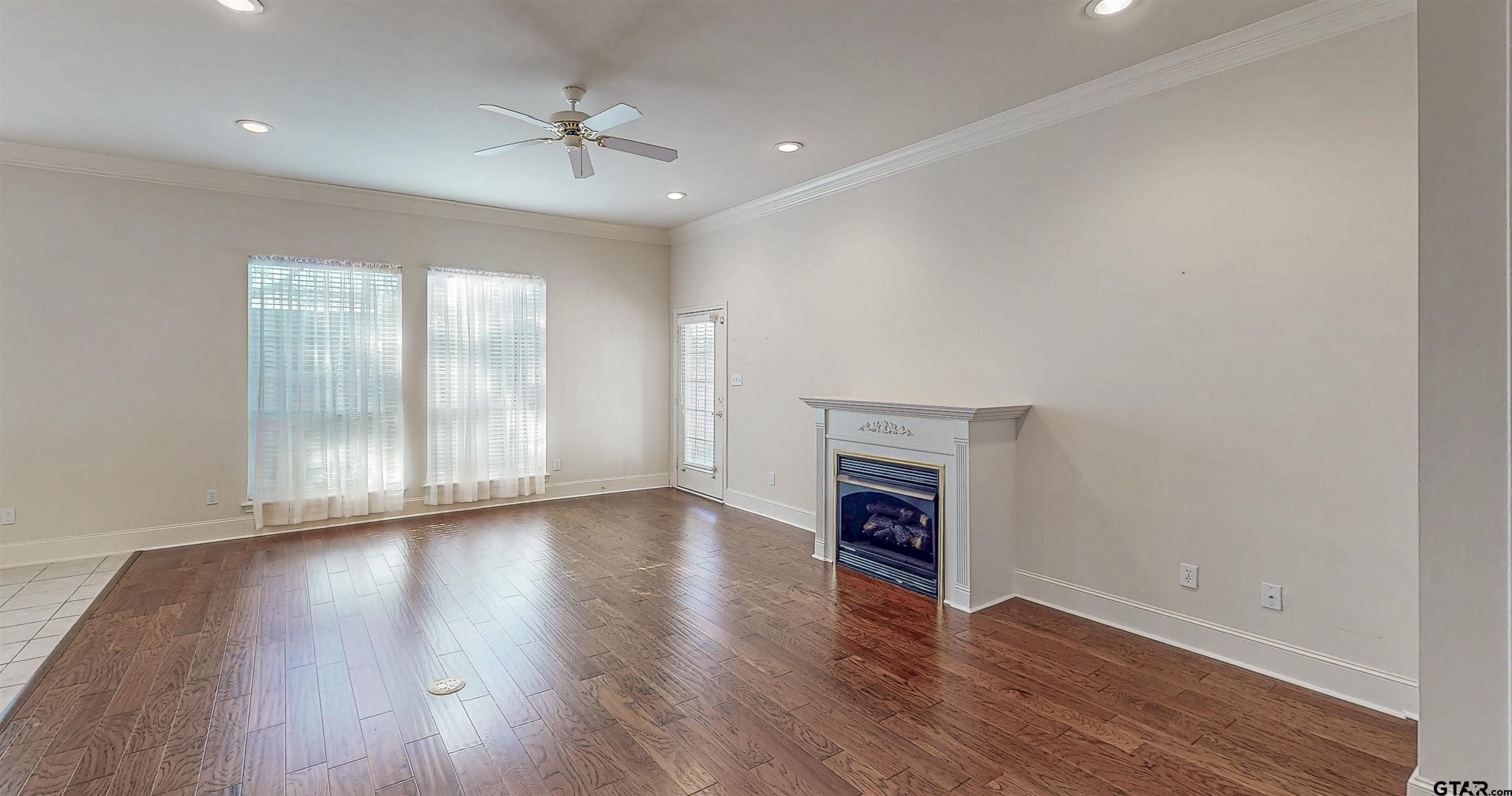 2435 Homestead Lane Tyler, TX 75701 - Photo 7 of 35 an empty room with wooden floor a ceiling fan and windows