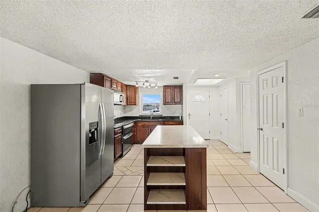 a kitchen with stainless steel appliances kitchen island granite countertop a refrigerator and a stove