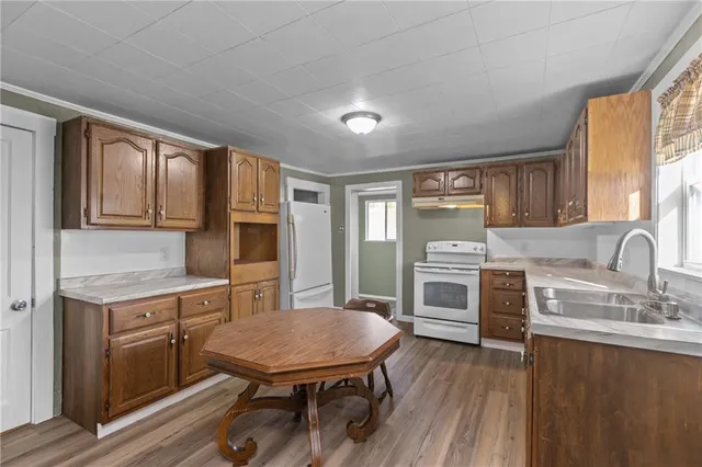 a kitchen with stainless steel appliances a stove a sink dishwasher a microwave oven and a dining table with wooden floor