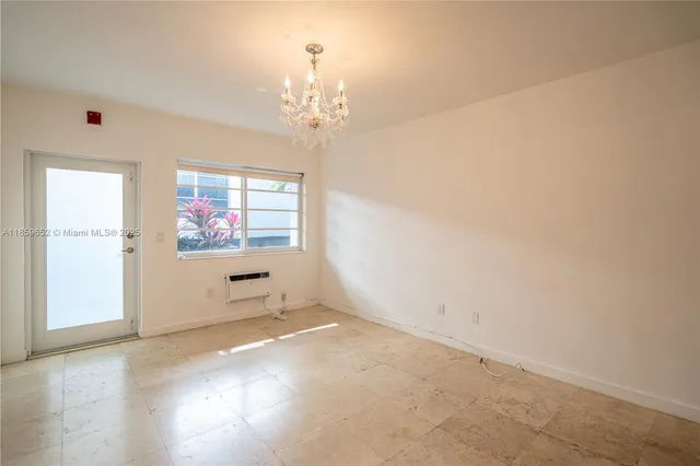 an empty room with chandelier fan and windows