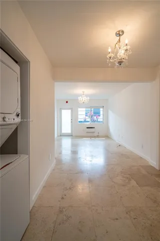 a view of a hallway with wooden floor and chandelier