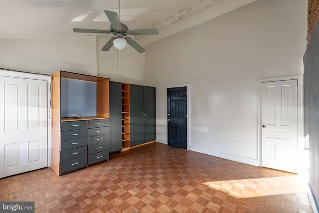 a view of an empty room with cabinet and a ceiling fan