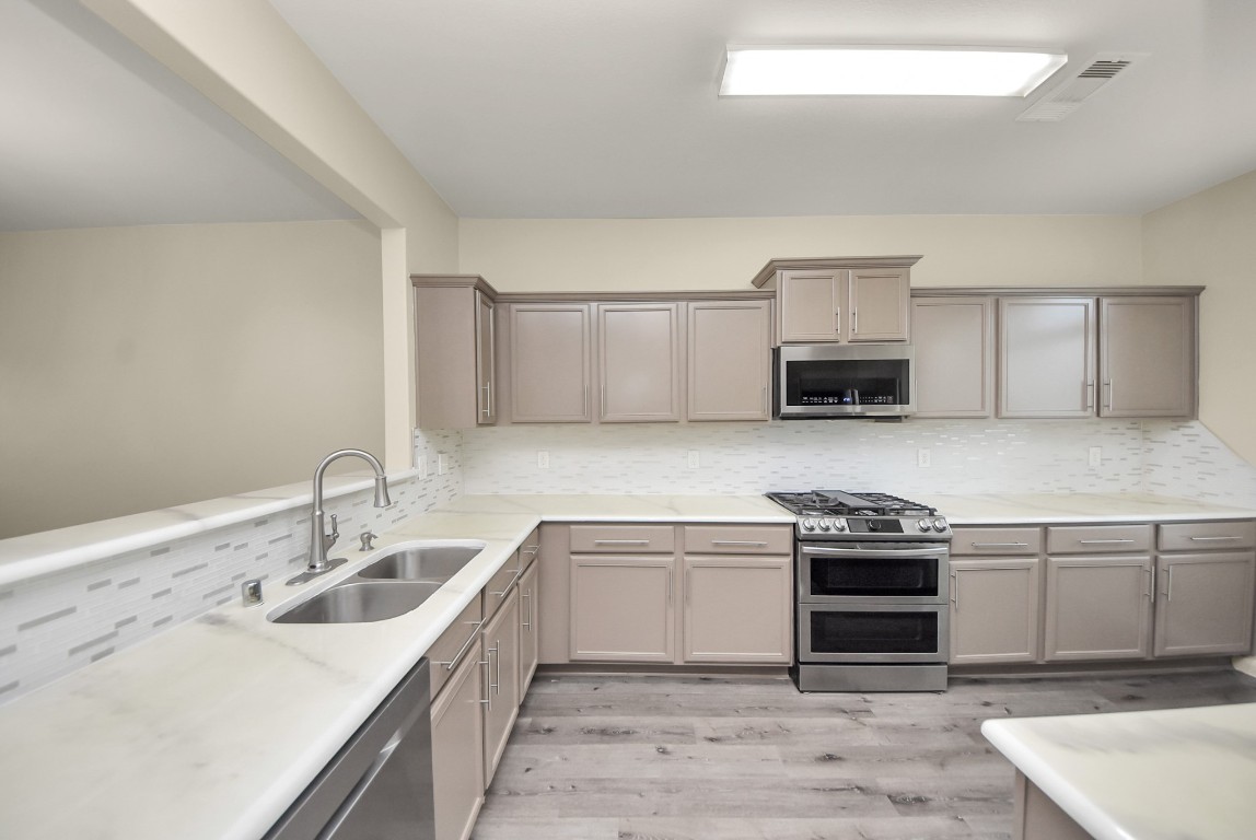 1855 Garnet Breeze Drive Rosharon, TX 77583 - Photo 8 of 38 a kitchen with stainless steel appliances granite countertop a sink stove oven and white cabinets