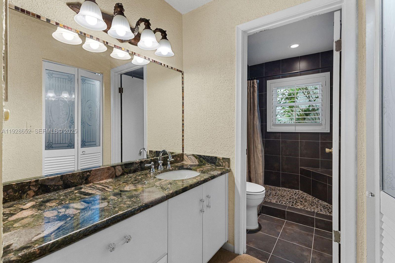 9871 Southwest 58th Court Cooper City, FL 33328 - Photo 15 of 54 a bathroom with a granite countertop sink a toilet and a mirror