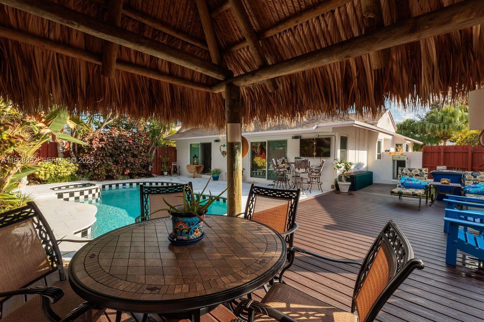 9871 Southwest 58th Court Cooper City, FL 33328 - Photo 38 of 54 a view of a patio with table and chairs potted plants and wooden floor