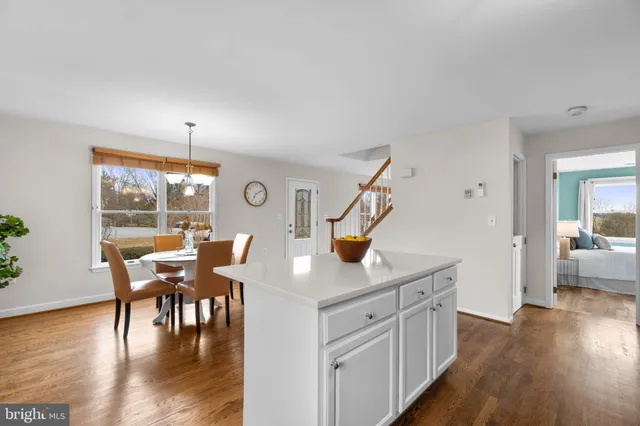 a kitchen with granite countertop a table chairs stove and wooden floor