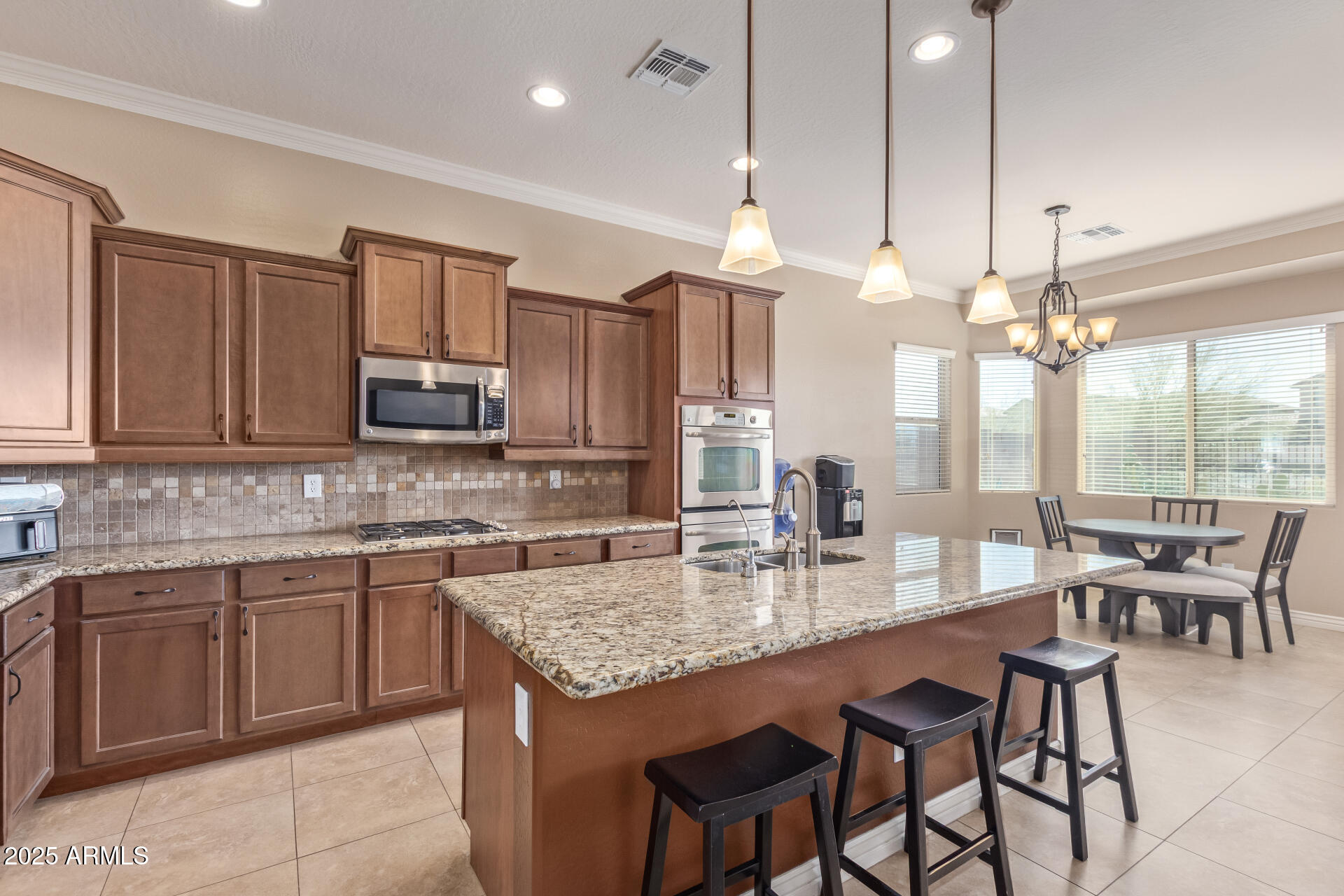 17743 West Verdin Road Goodyear, AZ 85338 - Photo 16 of 69 a kitchen with kitchen island granite countertop a table chairs sink and microwave