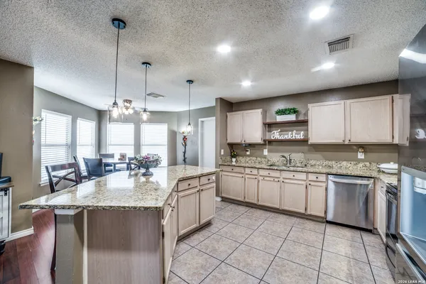 a large kitchen with granite countertop a sink dishwasher a stove and a refrigerator with wooden floor