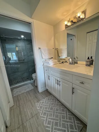 a bathroom with a sink a toilet a mirror and shower