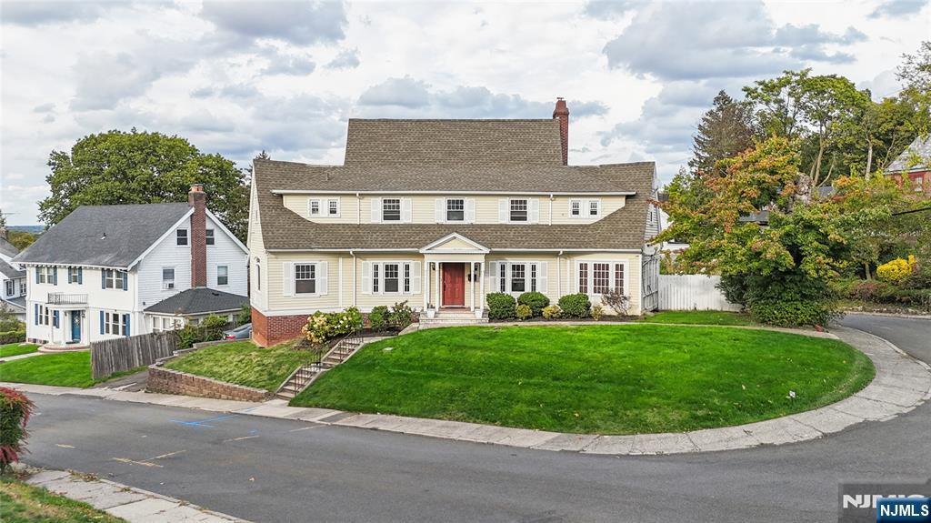 a view of a white house with a big yard and potted plants