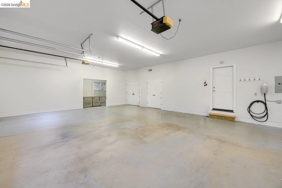 21950 Lyons Bald Mountain Road Sonora, CA 95370 - Photo 43 of 76 Spacious garage featuring a durable concrete floor, overhead fluorescent lighting, a dedicated entry door, and an electric vehicle charging station