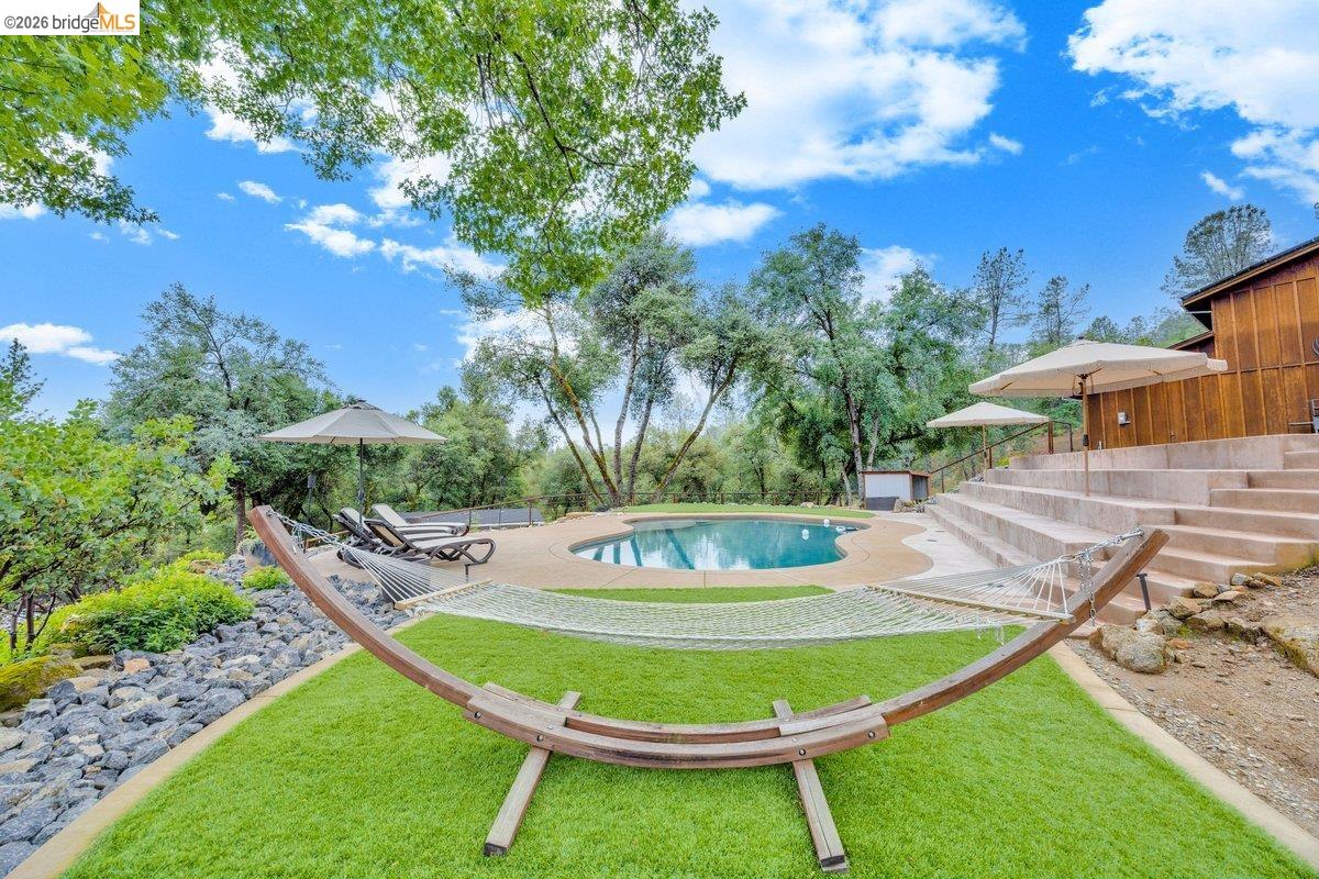 21950 Lyons Bald Mountain Road Sonora, CA 95370 - Photo 56 of 76 a view of a swimming pool with a table and chairs
