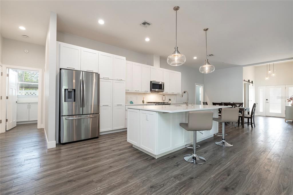 416 Indiana Avenue Crystal Beach, FL 34683 - Photo 7 of 60 a kitchen with stainless steel appliances a refrigerator a stove a sink a dining table and chairs with wooden floor