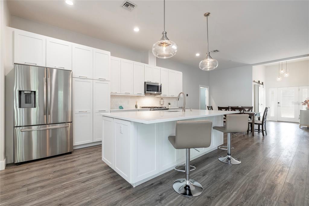 416 Indiana Avenue Crystal Beach, FL 34683 - Photo 8 of 60 a kitchen with stainless steel appliances granite countertop a refrigerator a stove a sink dishwasher a dining table and chairs with wooden floor