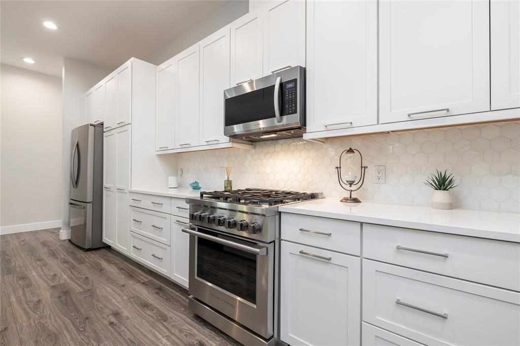 416 Indiana Avenue Crystal Beach, FL 34683 - Photo 10 of 60 a kitchen with stainless steel appliances white cabinets and a stove a oven with wooden floor