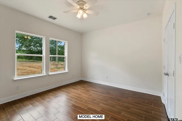 an empty room with wooden floor and windows
