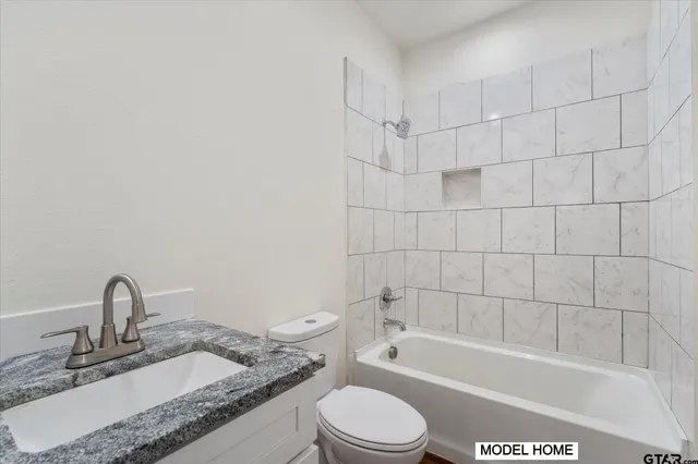 a bathroom with a granite countertop bathtub sink vanity mirror and toilet