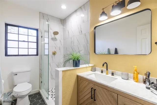a bathroom with a granite countertop sink mirror and toilet