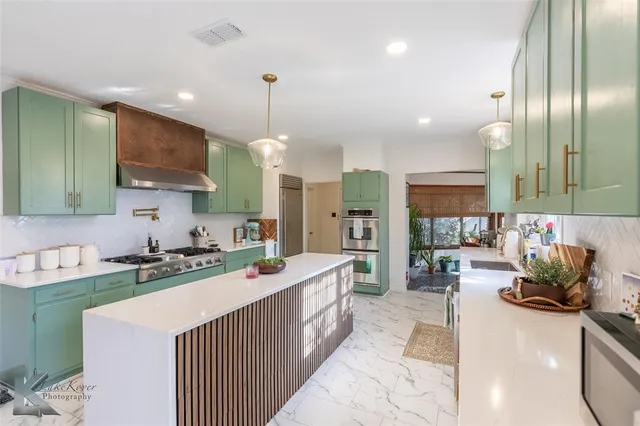 a kitchen with stainless steel appliances a sink a stove a refrigerator and cabinets
